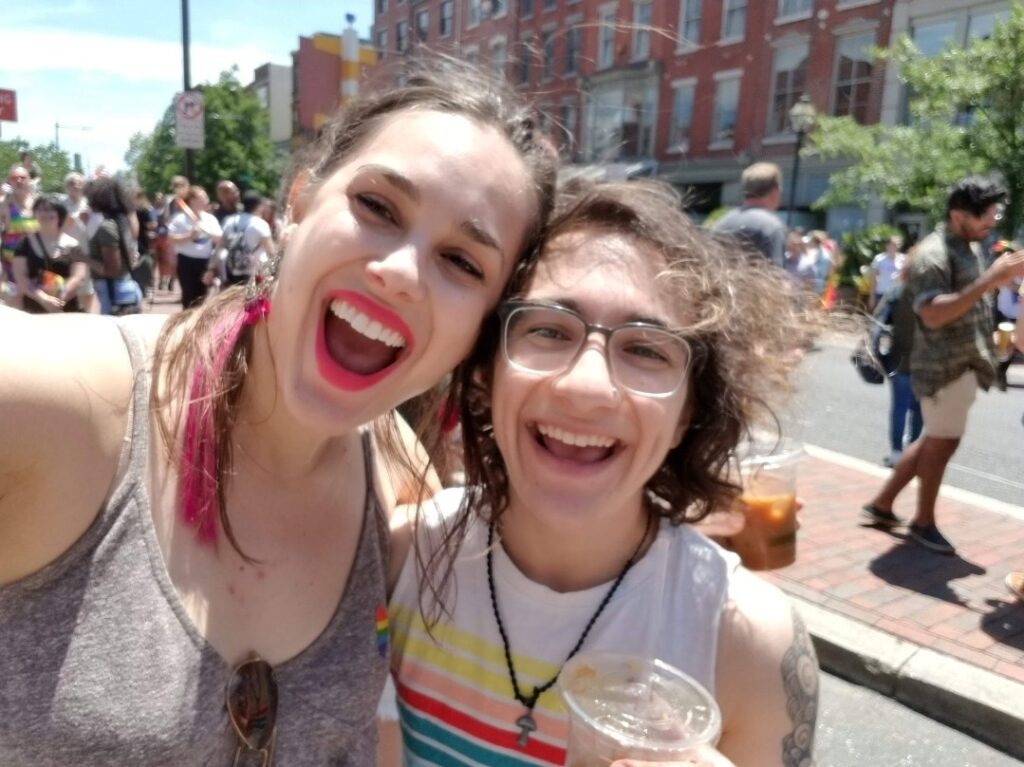 Tina (right) smiling with a friend at an outdoor street festival, before ME/CFS.