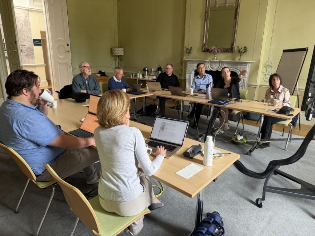 Researchers gathered around a conference table, discussing data during a collaborative workshop.